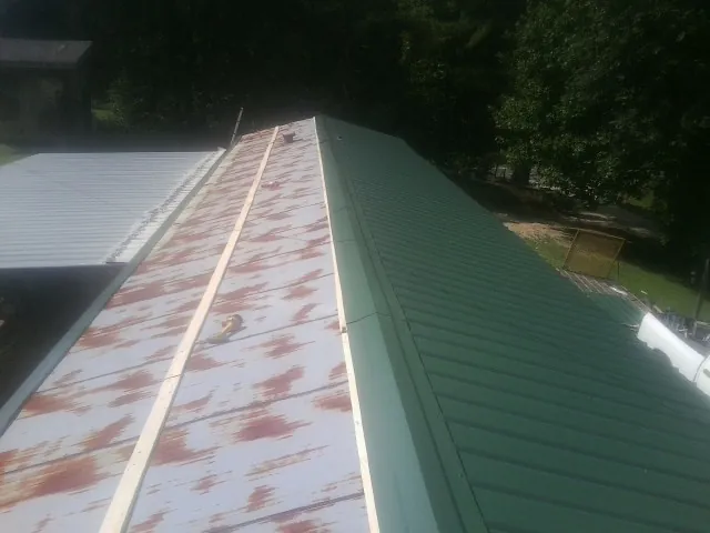 Old rusted panels beside newly installed green metal roofing — Wind Damage Roof Repair by Roofing Brothers in White Pine