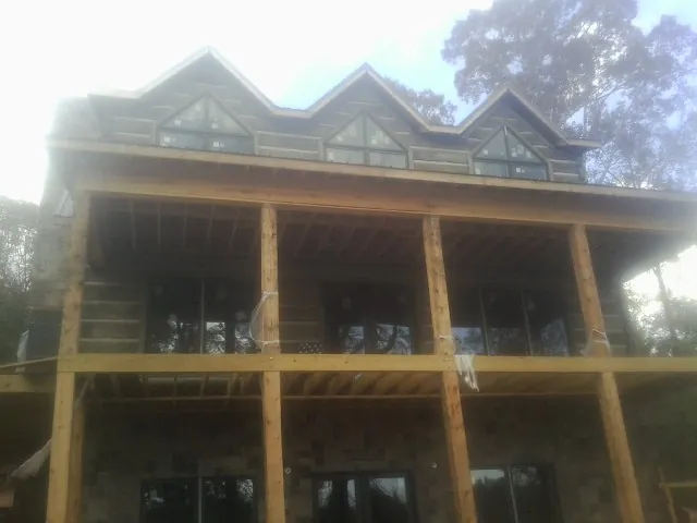 Dormers and porch framing on a large log home under construction — Roof Coating work by our crew in White Pine