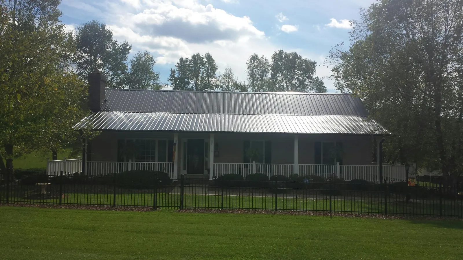 Gray metal roof on a brick ranch with a full width front porch — Gutter Guard Installation work by our crew in White Pine