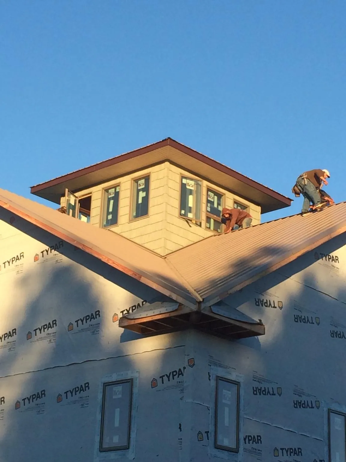 Roofers working around a rooftop cupola on a new metal roof at sunset — Roof Waterproofing in White Pine by Roofing Brothers